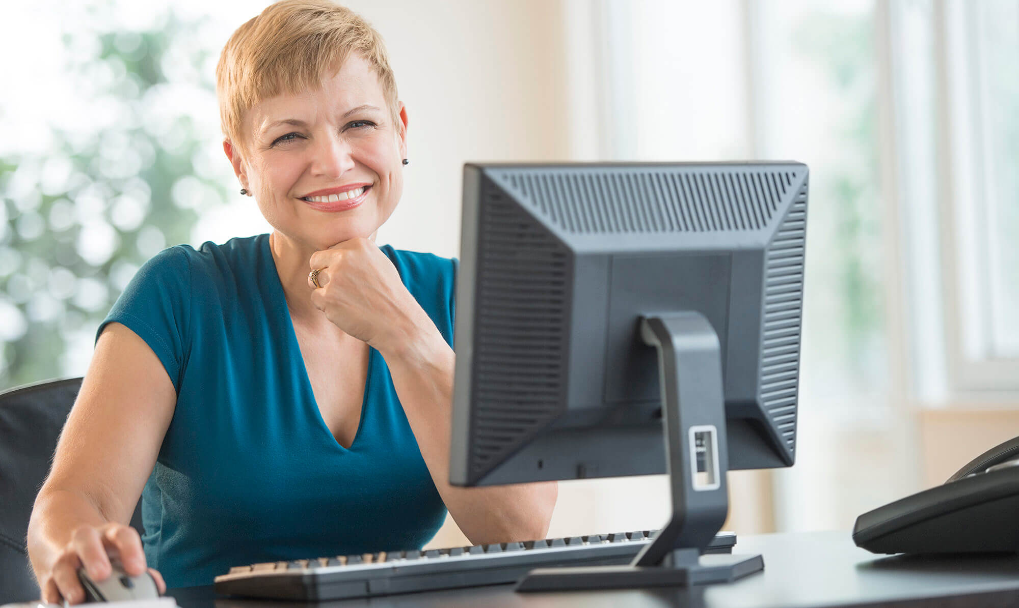 Happy Businesswoman Sitting At Computer Desk