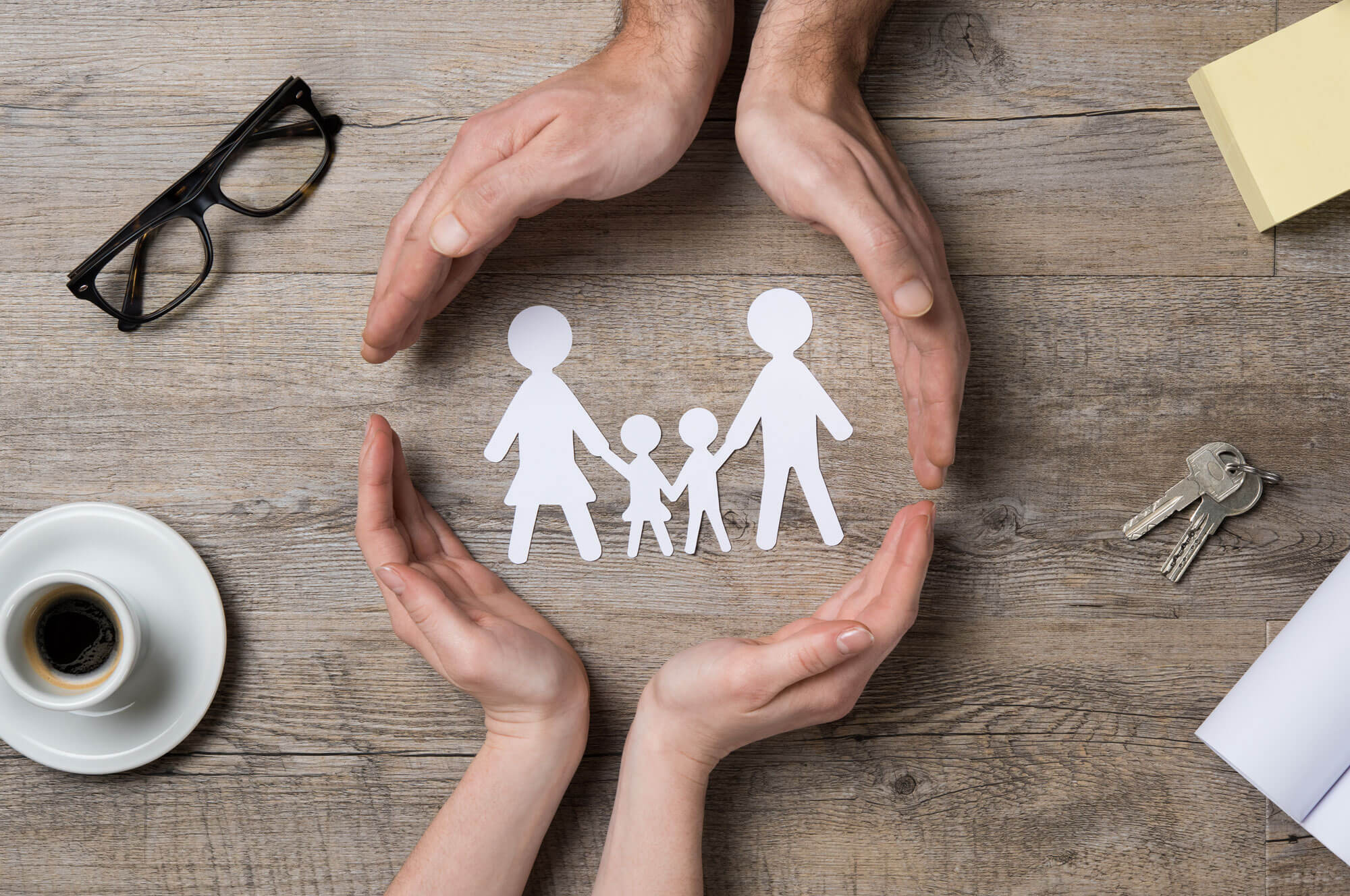 Paper cutout of a family with two adult hands making a circle around