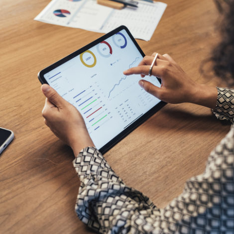Anonymous Businesswoman Analyzing Statistical Business Reports on her Tablet PC at the Office, a Close Up Hands of a woman sitting at her desk and doing financial analysis at work, a close up.